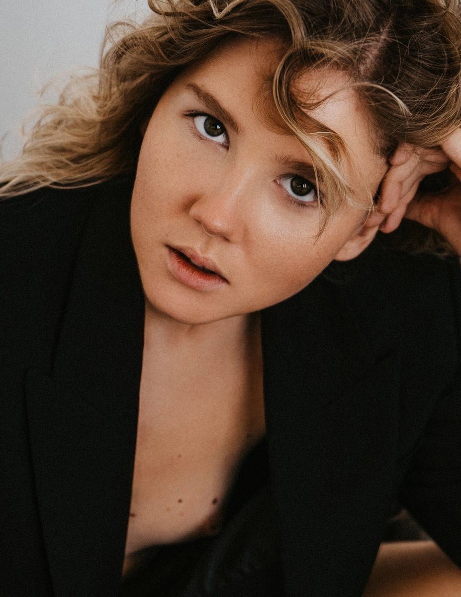 Portrait, woman with curly blonde hair in a black blazer